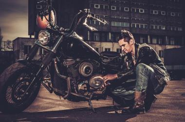 Biker repairing his custom motorcycle bobber on a road